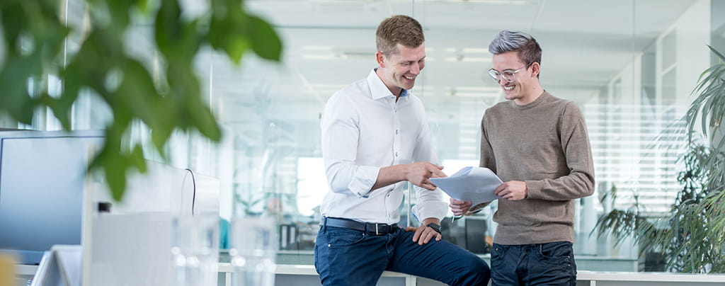 Weyland GmbH - Lächelnde Geschäftskollegen diskutieren im Büro